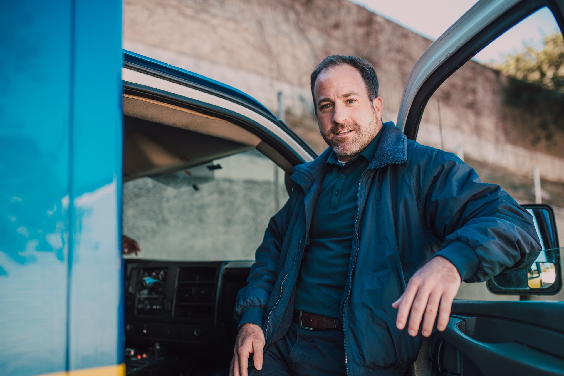 Smiling HVAC technician standing next to a service van